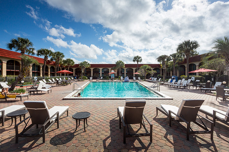 Portrait shot of the pool at our family friendly resort in Kissimmee, FL. Brick pavers, and an array of folding beach chairs on both sides of the pool
